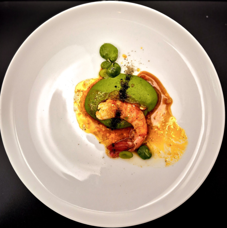 A plated course with green vegetables and sauce