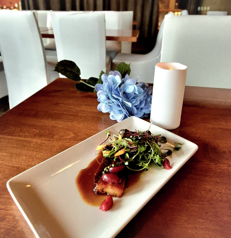 A plated course beside flowers and a candle on the table